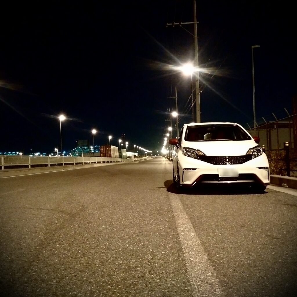 夜の街灯の下に停められた日産ノート NISMO S(E12改)の外装フロントビュー